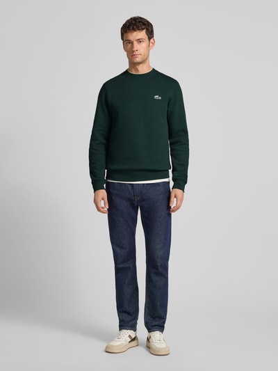 Männermodel trägt Regular Fit Sweatshirt aus reiner Baumwolle von Lacoste, Optik: Unifarben, Label-Patch, Sweat, Ganzkörperansicht von vorne.