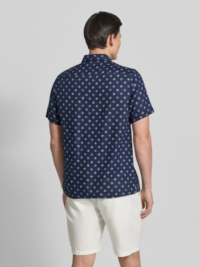 Männermodel trägt Regular Fit Leinenhemd mit Brusttasche von Scotch & Soda, Dunkelblau mit Allover-Motiv-Print, Ganzkörperansicht Rückansicht.