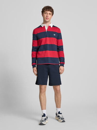 Männermodel trägt Shorts mit elastischem Bund und Label-Stitching von CHAMPION, dunkelblauer Baumwoll-Mix, Regular Fit, Ganzkörperansicht von vorne.