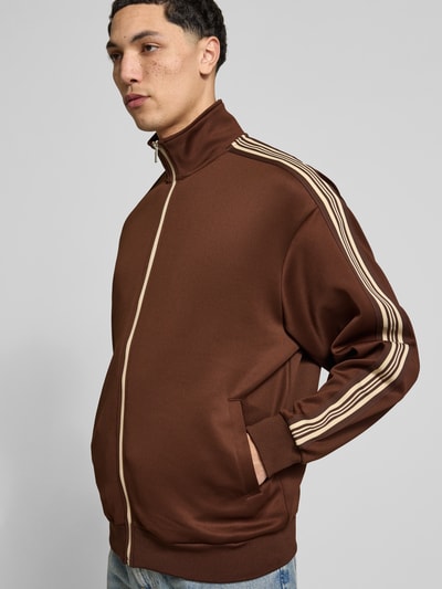 Männermodel trägt Relaxed Fit Sweatjacke mit Kontraststreifen Modell 'RIBER' von Only & Sons, Farbe Braun, Optik: Unifarben, Sweat, Ganzkörperansicht von vorne.