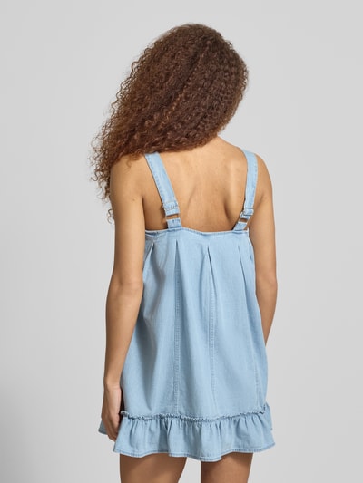 Frauenmodel trägt Jeanskleid aus reiner Baumwolle Modell 'OREGON' von Noisy May, hellblau, ärmellos, lockere Passform, Saumrüsche, Ganzkörperansicht Rückansicht.