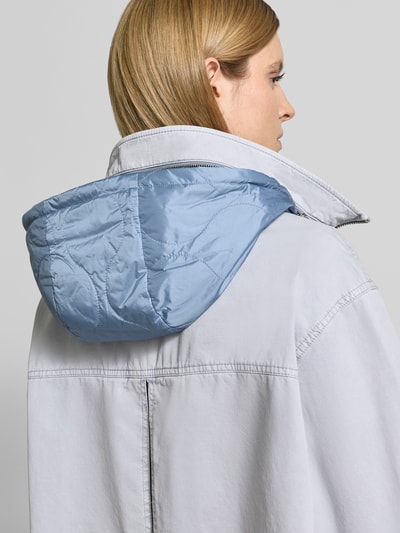 Männermodel trägt Jacke mit Stehkragen von Blonde No. 8 z bawełny, luźny krój, stójka, zamek błyskawiczny dwustronny, wpuszczane kieszenie, brustasza, jasnoniebieska, tekstura gładka, długość tyłu w rozmiarze 36: 61 cm, szerokość ramion w rozmiarze 36: 51 cm, szerokość klatki piersiowej w rozmiarze 36: 60 cm, długość rękawów w rozmiarze 36: 60 cm, detal kaptura, zdjęcie detaliczne pleców, perspektywa z tyłu