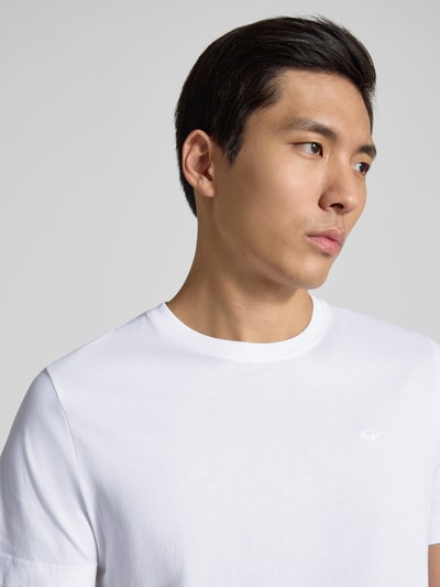Männermodel trägt Regular Fit T-Shirt aus reiner Baumwolle von Tom Tailor in Optik: Unifarben mit Logo-Stitching, Nahaufnahme Oberkörper.