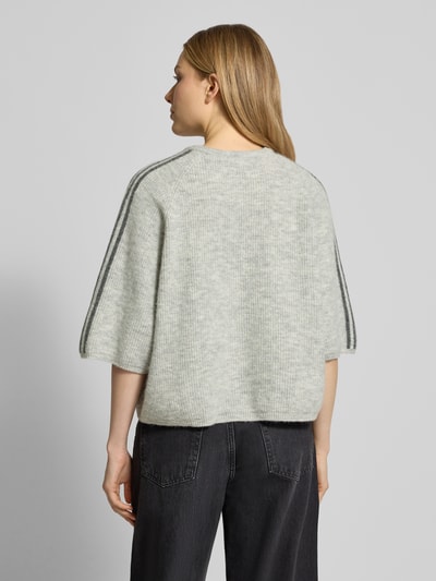 Vrouwenmodel draagt Cropped Strickpullover met geribbelde boorden Modell 'VITOW' van American Vintage in lichtgrijs, los vallende fit, rugaanzicht. Wol-alpaca-mix met stretch, ronde hals, label-stiksel, ruglengte 53 cm, mouwlengte 36 cm.