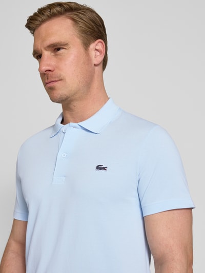 Männermodel trägt Regular Fit Poloshirt aus Baumwoll-Mix von Lacoste, Optik: Unifarben, Logo-Patch, Polokragen, Kurzarm, Nahaufnahme Oberkörper.