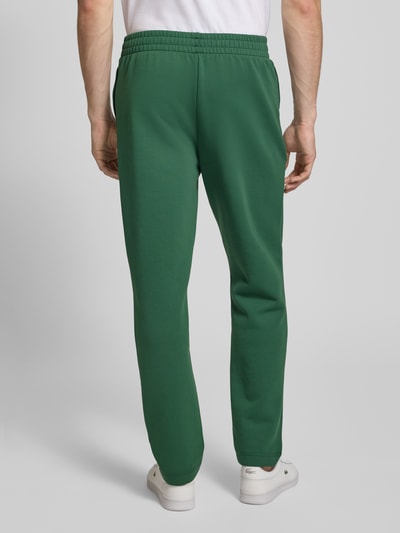 Mężczyzna nosi Tapered Sweatpants mit Baumwoll-Anteil od Lacoste Sport, zielony, jednolity, bawełna, krój tapered, widok całej sylwetki od tyłu.