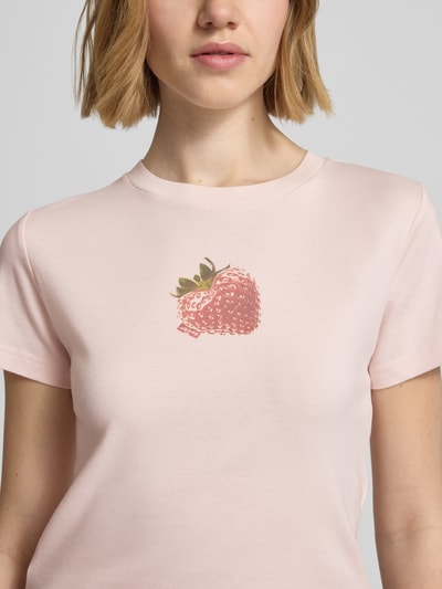 Frauenmodel trägt Regular Fit T-Shirt aus reiner Baumwolle von Levi's® in Rosa mit Erdbeer-Motiv-Print, unifarben, Nahaufnahme Oberkörper.