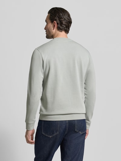 Männermodel trägt Relaxed Fit Sweatshirt aus reiner Baumwolle Modell 'WESTART' von BOSS Orange in Hellgrau, unifarben, Ganzkörperansicht Rückansicht.