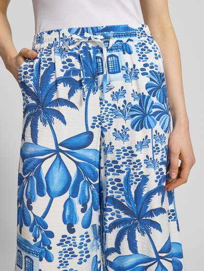 Vrouwenmodel draagt Culotte uit viscosemix met elastische band van Christian Berg Woman, blauw-wit patroon, steekzakken, los model, tunnelkoord, binnenbeenlengte 61 cm, bandwijdte maat 36 is 39 cm, Franse steekzakken, detailopname bovenbenen en band.