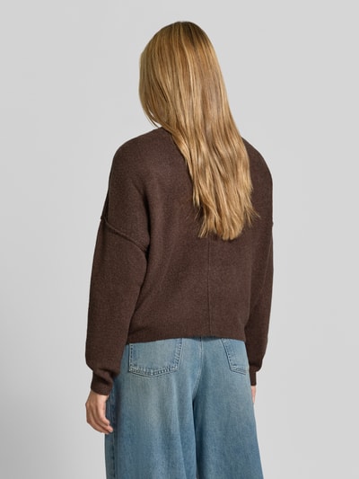 Frauenmodel trägt Relaxed Fit Strickpullover aus Material-Mix mit Leinen-Anteil von American Vintage, braun, gerippte Abschlüsse, Rückenansicht, Kontext: Damen Strickpullover, überschnittene Schultern, langärmlig, Rundhalsausschnitt, Größe XS/S Rückenlänge 50 cm, Ärmellänge 60 cm. Ganzkörperansicht Rückansicht