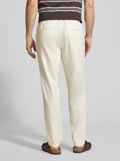 Męski model nosi Straight Fit Leinenhose mit elastischem Bund Modell 'Barton' von Matinique, mieszanka lnu i bawełny, kolor jasny, spodnie z prostymi nogawkami, elastyczny pas z tunelem, kieszenie z tyłu, szerokość w rozmiarze M: 34 cm, długość wewnętrzna nogawki w rozmiarze M: 78 cm, widok całej sylwetki z tyłu.
