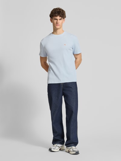 Männermodel trägt Regular Fit T-Shirt mit Logo-Patch von Calvin Klein Jeans aus Baumwoll-Mix, hellblau mit Strukturmuster, Ganzkörperansicht von vorne. Herren T-Shirt, Rundhalsausschnitt, Rückenlänge bei Größe M 68 cm.