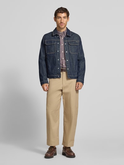 Männermodel trägt Loose Fit Weite Hose aus Baumwoll-Mix von Lacoste, beige Farbe, glatte Struktur, Ganzkörperansicht von vorne. Herren Weite Hose von Lacoste