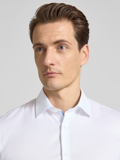 Männermodel trägt weißes Super Slim Fit Business-Hemd mit Kentkragen von OLYMP No. Six aus Baumwoll-Elasthan-Mix, Nahaufnahme Oberkörper.