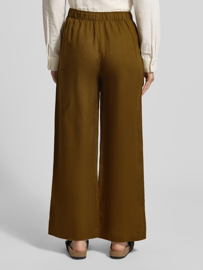 Frauenmodel trägt Leinenhose mit elastischem Bund Modell 'LINO' von Mango in Braun, Reines Leinen, Relaxed-Fit, Ganzkörperansicht Rückansicht.