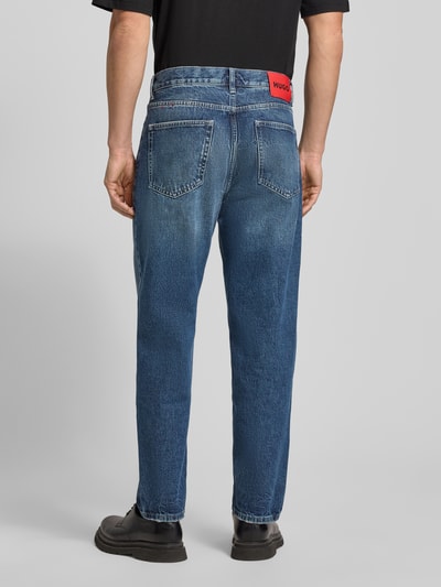 Męski model nosi Relaxed Fit Jeans aus reiner Baumwolle Modell 'HUGO 838' od HUGO, niebieski denim z czerwonym logo, gładka faktura, pełny tył.