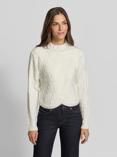 Frauenmodel trägt Strickpullover mit Woll-Anteil in Wickel-Optik von Apricot, cremefarben, Zopfmuster, Stehkragen, Regular Fit, Ganzkörperansicht von vorne.