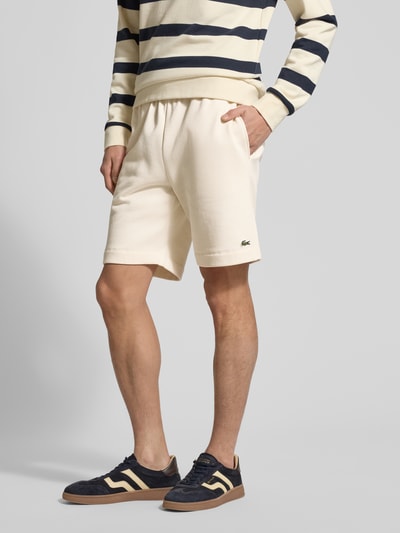 Mannenmodel draagt Regular Fit Sweatshorts aus Baumwoll-Mix van Lacoste in effen kleuren, katoenmix sweat met zij-steekzakken, labelpatch, elastische boord met tunnelkoord, achterzak, ganzkörperansicht van voren.