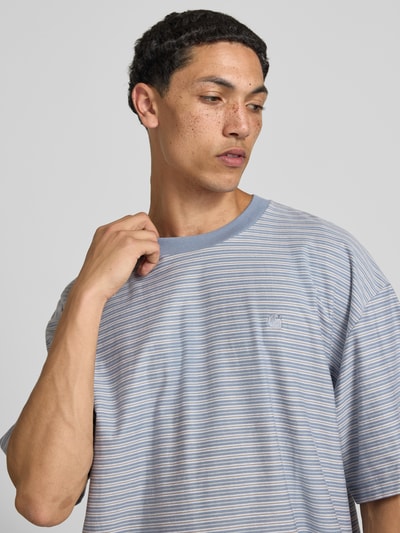 Männermodel trägt Herren T-Shirt von Carhartt Work In Progress aus Reine Baumwolle, Boxy-Fit, Rundhalsausschnitt, Logo-Stitching, Nahaufnahme Oberkörper. Modell 'Dupree', Rückenlänge bei Größe M: 70 cm, feine blaue und weiße Streifen mit weicher Stoffstruktur.