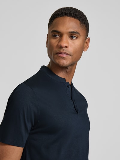 Männermodel trägt Slim Fit Poloshirt mit Stehkragen Modell 'LOUIS' von Drykorn aus Baumwoll-Modal-Mix in Dunkelblau, Nahaufnahme Oberkörper.