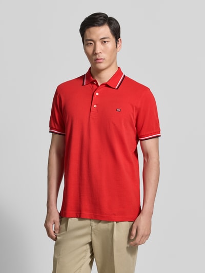 Męski model nosi Regular Fit Poloshirt mit Kontraststreifen od Christian Berg Men, czysta bawełna, czerwony, krój regular fit, listwa guzikowa, długość tyłu 71 cm w rozmiarze M, całkowity widok z przodu.