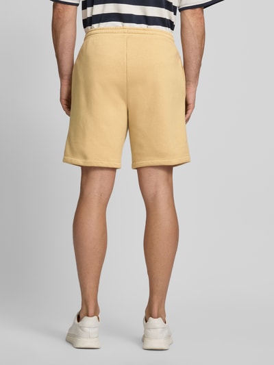 Männermodel trägt Sweatshorts mit Logo und elastischem Bund von GAP aus Baumwoll-Mix in Gelb, Regular-Fit, Eingrifftaschen, Ganzkörperansicht Rückansicht.