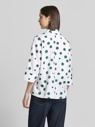 Frauenmodel trägt Relaxed Fit Hemdbluse mit 3/4-Arm von Christian Berg Woman, weiß mit grünen Punkten, reine Baumwolle, Hemdblusenkragen, durchgehende Knopfleiste, Rückenlänge 57 cm, Ärmellänge 65 cm bei Größe 36, Ganzkörperansicht Rückansicht.