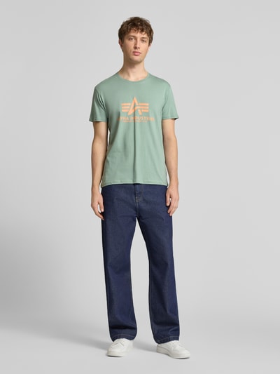Männermodel trägt T-shirt mit Labeldetail Modell 'BASIC' von Alpha Industries in mint, recht model, puur katoen, ronde hals, ruglengte maat M 69 cm, Ganzkörperansicht von vorne