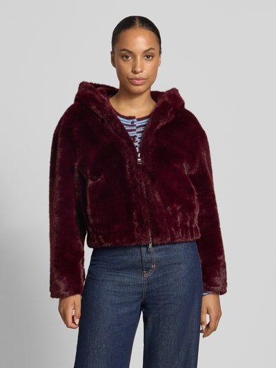 Vrouwenmodel draagt Jacke aus Kunstfell mit Zweiwege-Reißverschluss van Blonde No. 8 in bordeaux, regular fit, kap, vooraanzicht, lengtemaat 50 cm, schouderbreedte 50 cm, borstwijdte 60 cm, mouwlengte 73 cm, detailrijke zachte textuur. Ganzkörperaanzicht van voren.