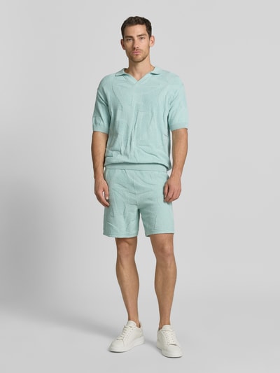 Männermodel trägt Relaxed Fit Poloshirt aus reiner Baumwolle Modell 'ASURFO' von BOSS Orange in Hellblau, Frottee-Struktur, Ganzkörperansicht von vorne.