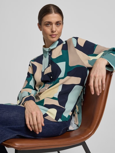 Frauenmodel trägt Relaxed Fit Hemdbluse aus reiner Viskose von Tom Tailor mit Allover-Muster, Schleifen-Details, Nahaufnahme Oberkörper.