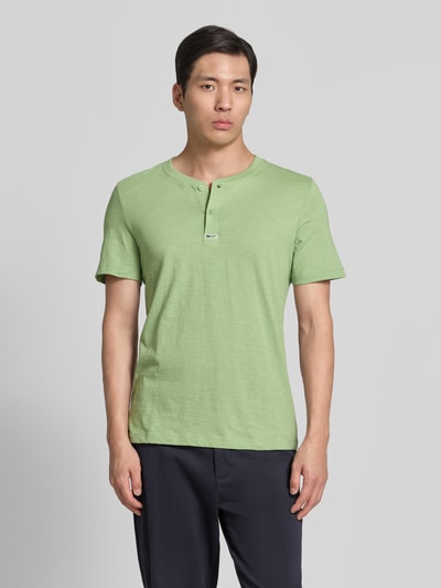 Männermodel trägt Regular Fit T-Shirt aus reiner Baumwolle von s.Oliver RED LABEL in Optik: Unifarben, Henley-Kragen, Ärmelform: Kurzarm, Ganzkörperansicht von vorne.