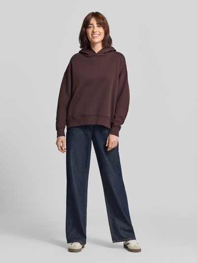 Frauenmodel trägt Oversized Hoodie aus Baumwolle von Closed in Dunkelbraun mit Print und überschnittenen Schultern, Ganzkörperansicht von vorne.