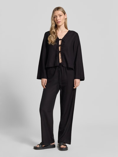 Frauenmodel trägt schwarze Stoffhose aus Viskose-Mix Modell 'PRISILLA' von Vila, Wide-Leg, Eingrifftaschen, Tunnelzug, Ganzkörperansicht von vorne.