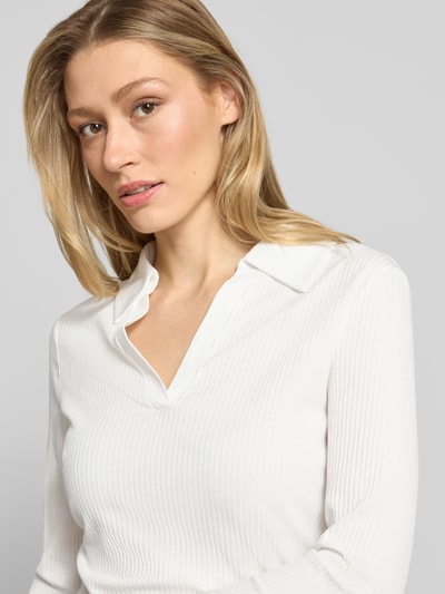 Kobieta nosi Longsleeve aus Viskose-Mix mit Polokragen Modell 'Seti' od OPUS, biały, krój regular fit, rippowana faktura, dekolt V, z przodu, zbliżenie na górną część ciała.