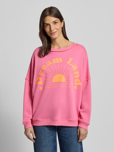 Frauenmodel trägt Oversized Sweatshirt mit gerippten Abschlüssen von miss goodlife in Pink mit gelbem Statement-Print, Nahaufnahme Oberkörper.