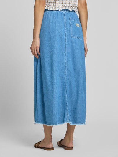 Kobieta modelka nosi spódnicę midi z bawełny w linii a, tkanina stylizowana na denim, frędzle, model 'IZEWAY' od American Vintage, szerokość w rozmiarze s: 35 cm, całkowita długość: 81 cm, widok całej sylwetki z tyłu