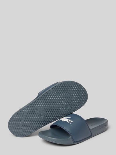 Produktfoto, Badeschuhe mit Logo Print Modell 'SERVE SLIDE' von Lacoste, Optik: Unifarben, Schuhspitze: Abgerundet, Absatzform: Flach, Applikation: Logo-Print, Verschluss: Schlupf/offen, Sohle: Strukturiert, in Dunkelblau.