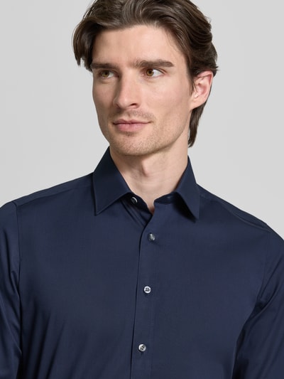 Mannelijk model draagt Regular Fit Businesshemd met extra langem Arm van OLYMP Level Five, effen donkerblauw, katoenmengsel, Kentkraag, doorknoopsluiting, sportmanchet, Nahaufnahme bovenlichaam.