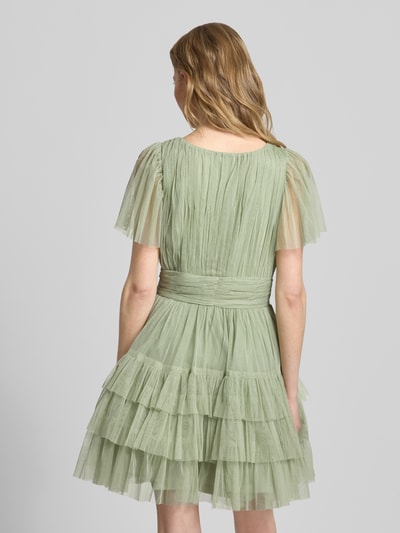 Frauenmodel trägt Cocktailkleid mit tiefem V-Ausschnitt von LACE & BEADS in Hellgrün, Tüll, A-Linie, Stufen-Look, Ganzkörperansicht Rückansicht.