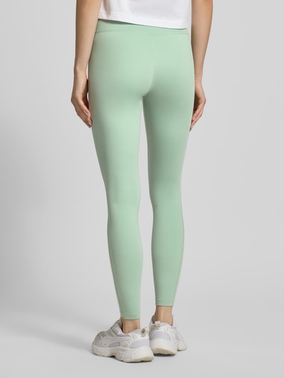 Frauenmodel trägt mintgrüne Leggings mit Logo-Print Modell 'One' von NIKE TRAINING aus Material-Mix mit Stretch-Anteil, Slim-Fit, elastischer Bund, Ganzkörperansicht Rückansicht.