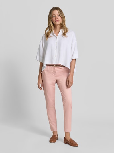 Frauenmodel trägt Hose in verkürzter Passform mit Gürtel von Christian Berg Woman aus Baumwoll-Viskose-Mix in Slim-Fit, zartrosa Farbton, glatte Struktur, Ganzkörperansicht von vorne.