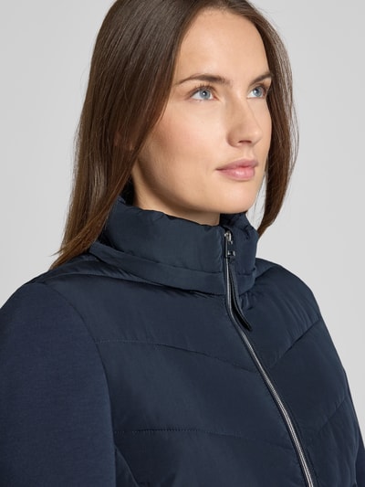 Vrouwenmodel draagt Slim Fit Steppjacke met gefüttertem Stehkragen van Christian Berg Woman Selection, donkerblauw, gewatteerde structuur, ritssluiting, zakken met ritssluiting, gevoerde opstaande kraag, capuchon met kraag, nahaufnahme bovenlichaam.