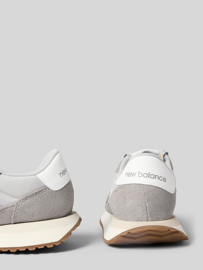 Produktfoto, Sneaker aus Leder-Mix von New Balance in Grau und Weiß mit Label-Detail und profilierter Sohle, Kontext: Damen Sneaker, angerundete Spitze, Schnürung, Absatzhöhe 3 cm, Schafthöhe 8 cm, Schaftweite 9 cm.