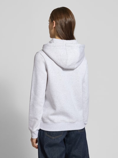 Frauenmodel trägt Regular Fit Sweatjacke aus Baumwoll-Mix von Tommy Jeans in Hellgrau-Melange, Kapuze, lange Ärmel, Ganzkörperansicht Rückansicht.