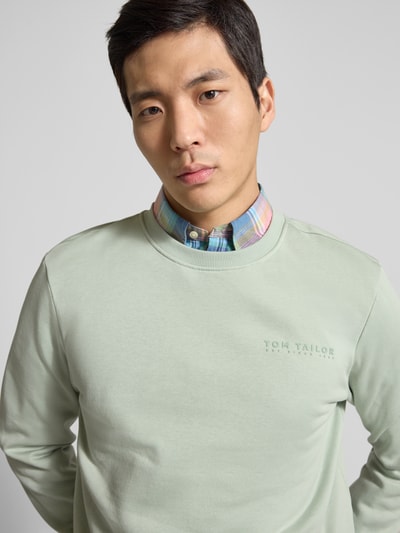 Męski model nosi Regular Fit Sweatshirt aus Baumwoll-Mix von Tom Tailor, efekt: jednolity kolor, nadruk z logo, okrągły dekolt, długi rękaw, zakończenia prążkowane, dzianina dresowa, mieszanka bawełny, zbliżenie na górną część ciała.