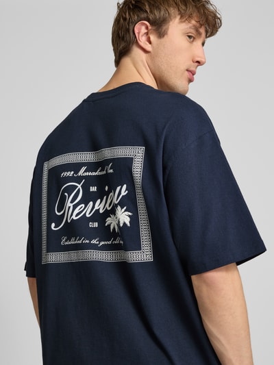 Männermodel trägt T-Shirt mit Rundhalsausschnitt und Label-Print von REVIEW in Dunkelblau, Relaxed-Fit, Reine Baumwolle, Rückenlänge 71 cm, Ganzkörperansicht Rückansicht.