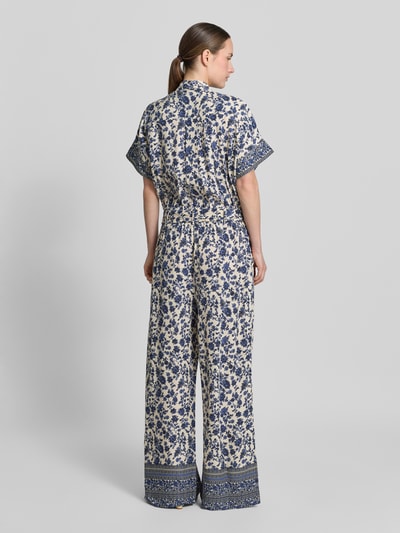 Vrouwenmodel draagt jumpsuit uit zuiver viscose met strikceintuur model 'Mathilde' van LOLLYS LAUNDRY, all-over look, relaxed fit, overhemdkraag, ruglengte maat S 46 cm, borstwijdte 44 cm, mouwlengte 17 cm, totale lengte 160 cm, binnenbeenlengte 77 cm, blauw-wit patroon, rechte pijpen, detail op zoom, model van achteren, volledig lichaam.