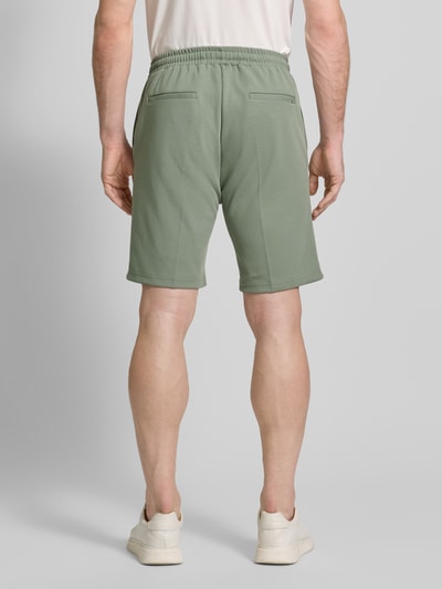 Mannelijk model draagt Regular Fit Shorts met tunnelkoord van Antony Morato in materiaalmix met katoen, bandplooien, bandwijdte 41 cm, binnenbeenlengte 25 cm, heren short, band en zakken in zachtgroene kleur, bandplooien design, geheelachteraanzicht