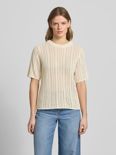 Frauenmodel trägt Regular Fit Strickshirt aus reiner Baumwolle Modell 'NUKA' von Pieces mit Optik:Allover-Muster, gestreift, Lochstrick, Rundhals, Kurzarm, cremefarbene Struktur, Ganzkörperansicht von vorne.
